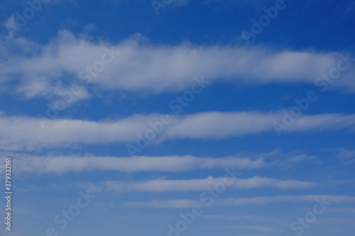 White feather clouds against the blue sky. Striped sky. Background.