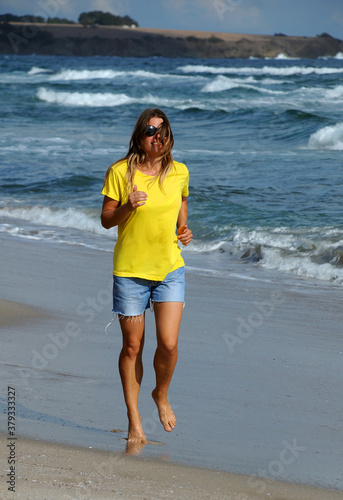 Young beautiful girl runs on the beach