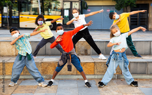 Modern tweens in protective face masks dancing hip-hop on summer street. New urban lifestyle concept during coronavirus. Conscious generation