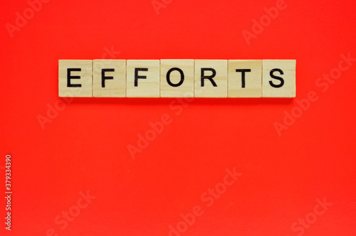 Word efforts. Wooden blocks with lettering on top of red background. Top view of wooden blocks with letters on red surface