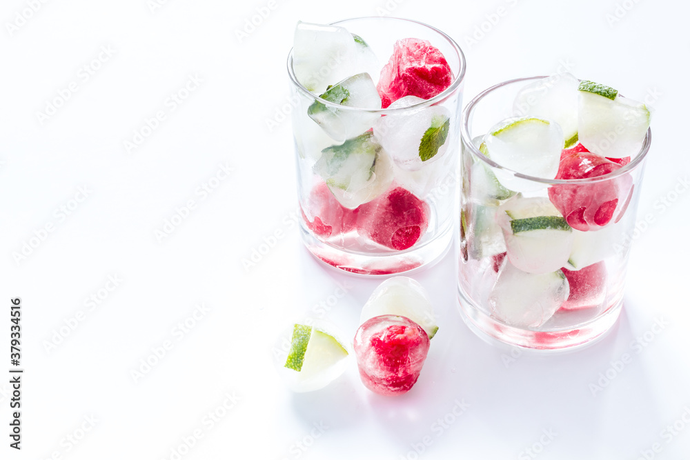 Cocktail glasses with berries in ice cubes on white table copy space Cocktail glasses with berries in ice cubes on white table copy space