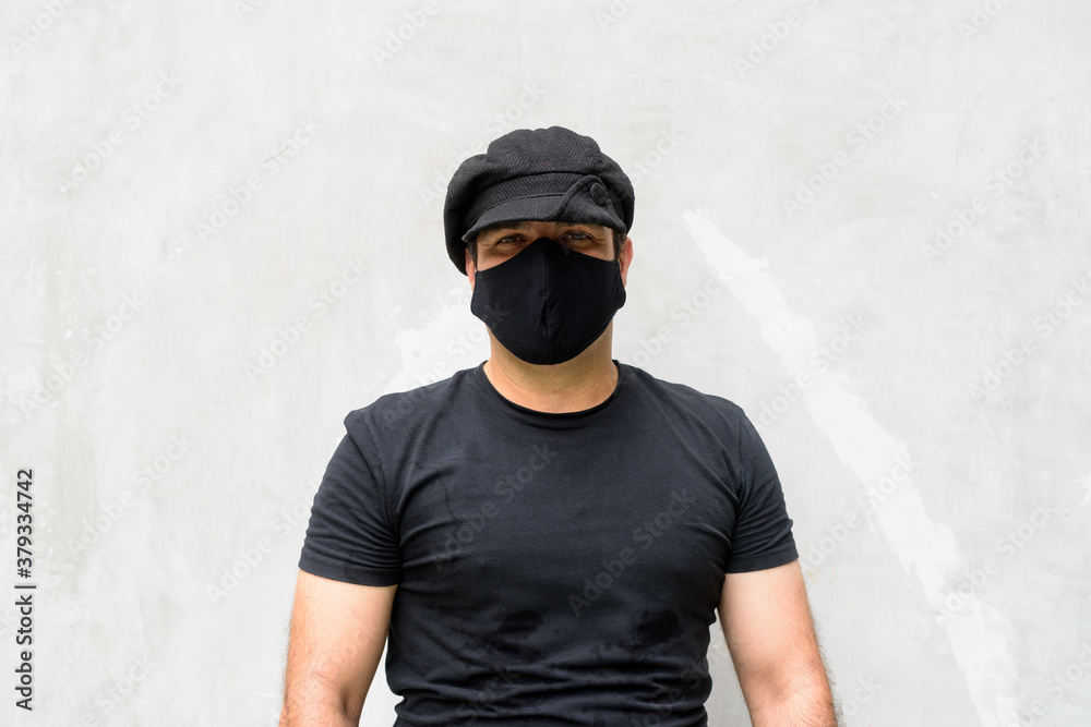 Portrait of Persian man wearing hat and mask against concrete wall Portrait of Persian man wearing hat and mask against concrete wall