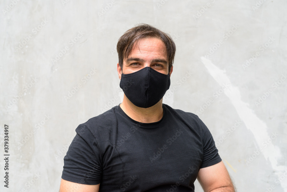 Portrait of Persian man with mask against concrete wall outdoors Portrait of Persian man with mask against concrete wall outdoors