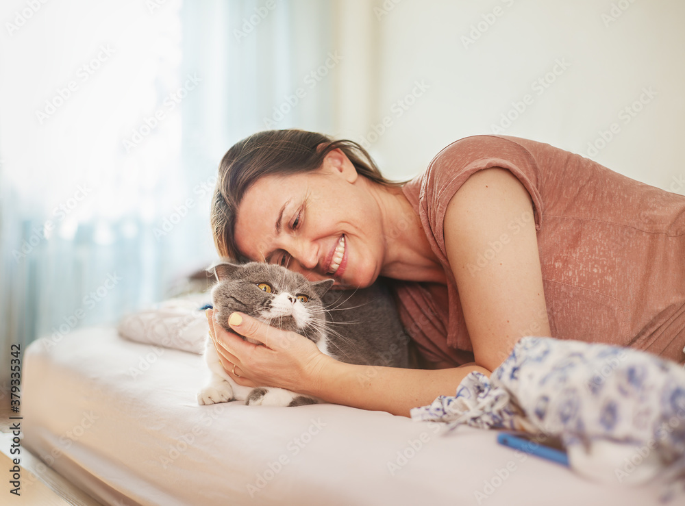 Happy woman in the bedroom hugs her cat. Happy woman in the bedroom hugs her cat.