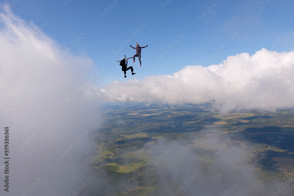 Fototapeta premium Skydiving. Two skydivers are flying and having fun above white clouds.