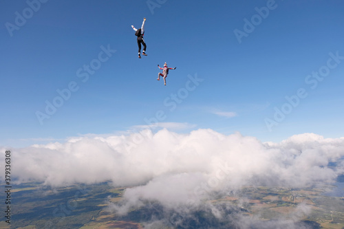 Skydiving. Two skydivers are flying and having fun above white clouds.