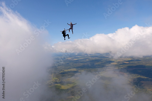 Skydiving. Two skydivers are flying and having fun above white clouds.