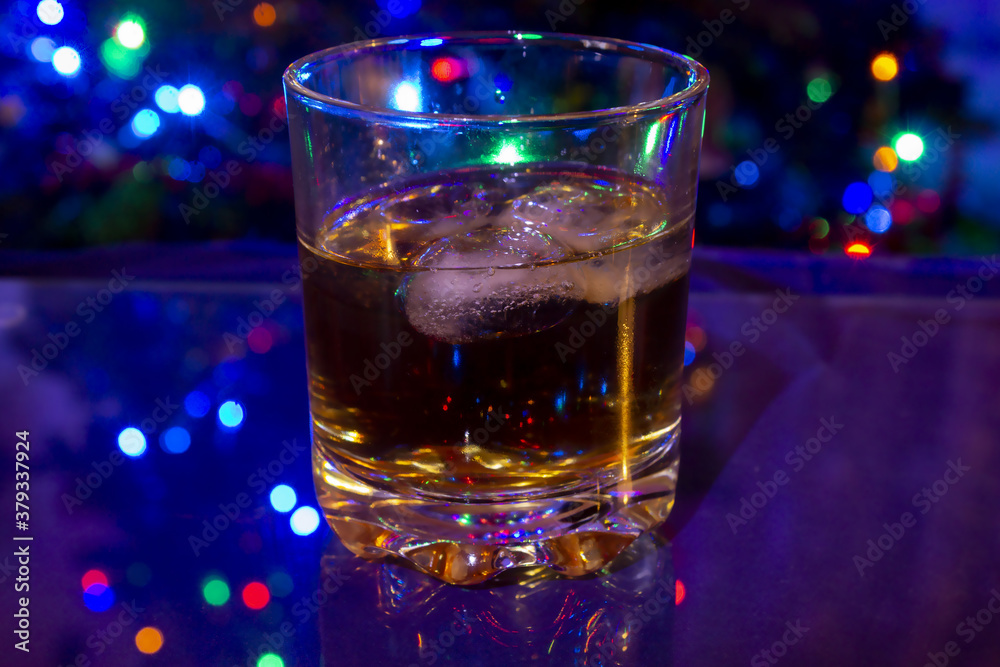 Glass with whisky and ice cubes blue background