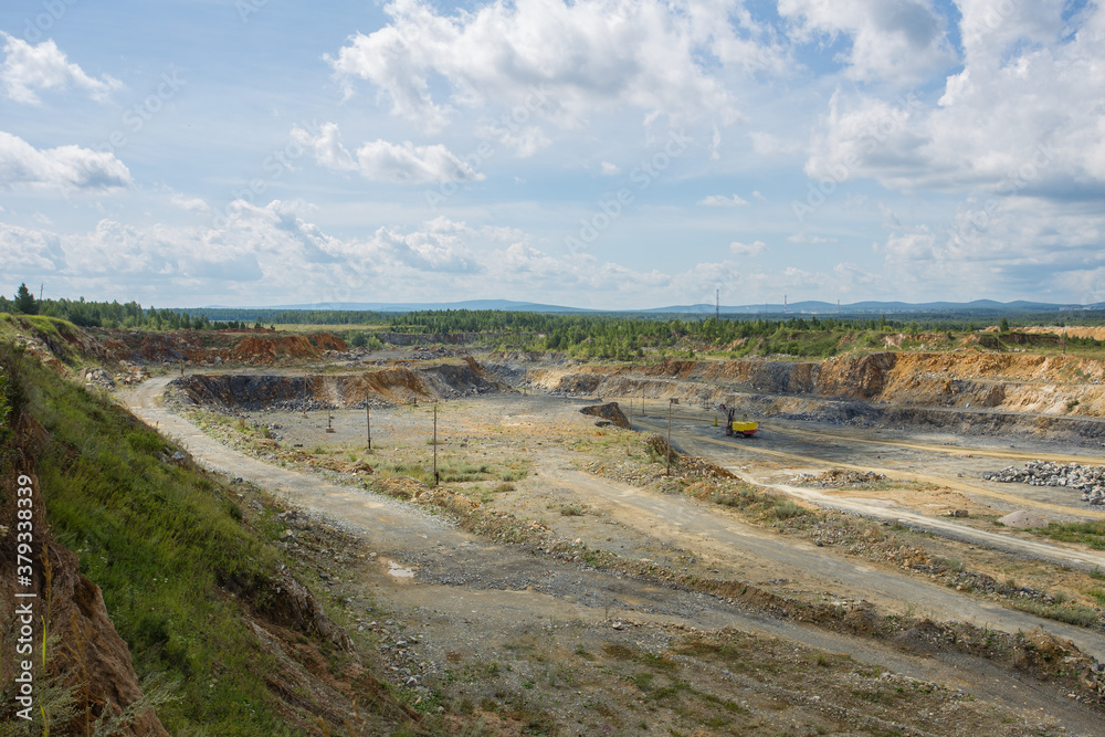 Big open pit limestone quarry mine with working drilling machines, excavators, trucks