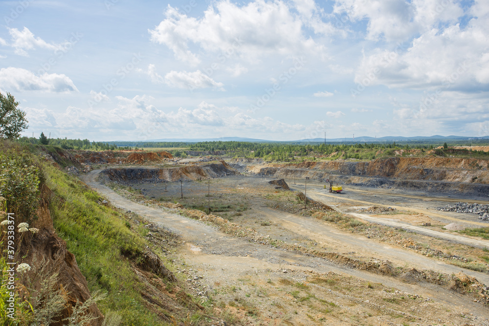 Big open pit limestone quarry mine with working drilling machines, excavators, trucks