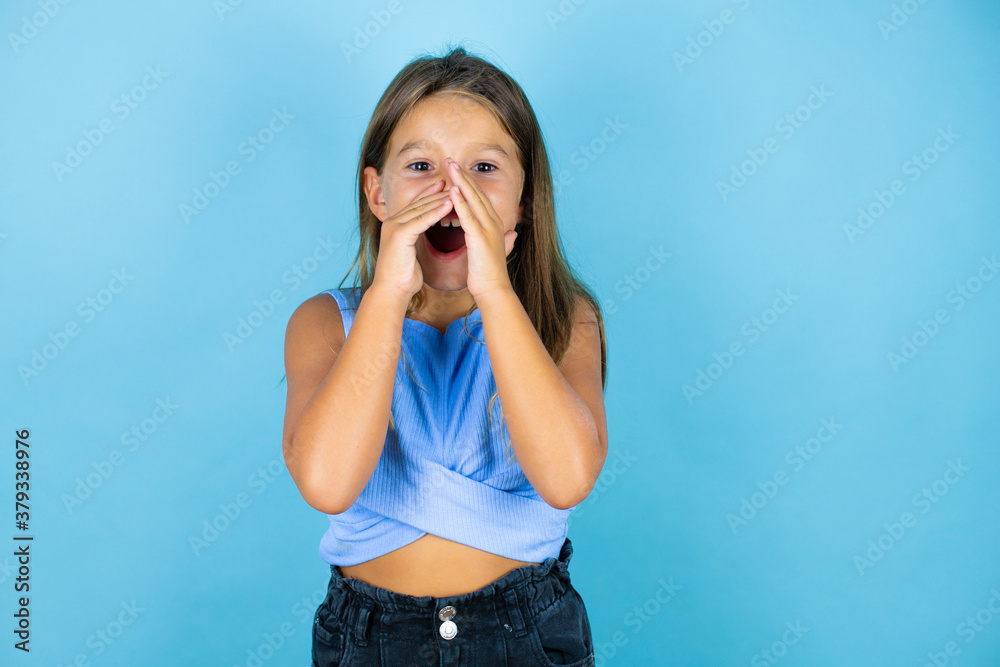 Young beautiful child girl over isolated blue background shouting and screaming loud to side with hands on mouth Young beautiful child girl over isolated blue background shouting and screaming loud to side with hands on mouth