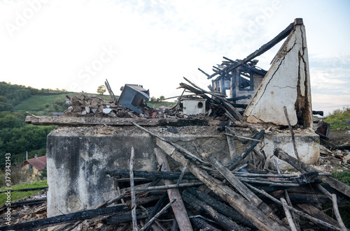 Ruins of building after the fire. House burnt by fire. Old ruined and demolished house in village. Destroyed home during the war. Burned wooden beams, doors and interior. People loose their house.