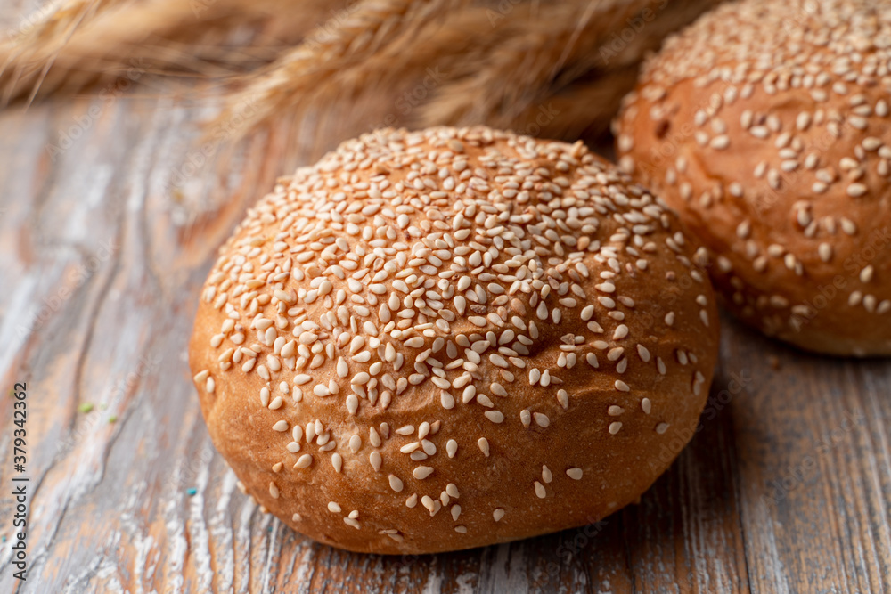 Whole grain wheat buns with sesame, on a rustic wooden table