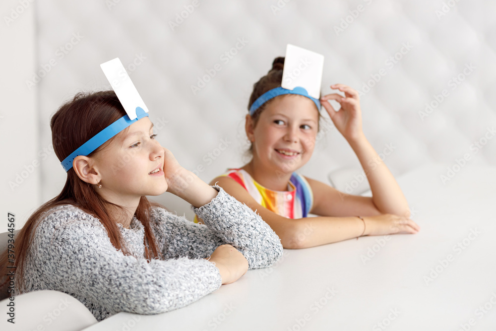 Girls Playing guess sticker. Children playing a game. Smile. Card on