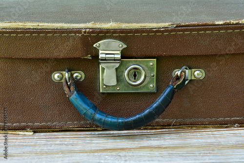 Canvas-taulu old suitcase lies on a shabby wooden table, front view close-up