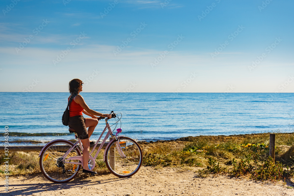 Woman ride bicycle on beach, active lifestyle.
