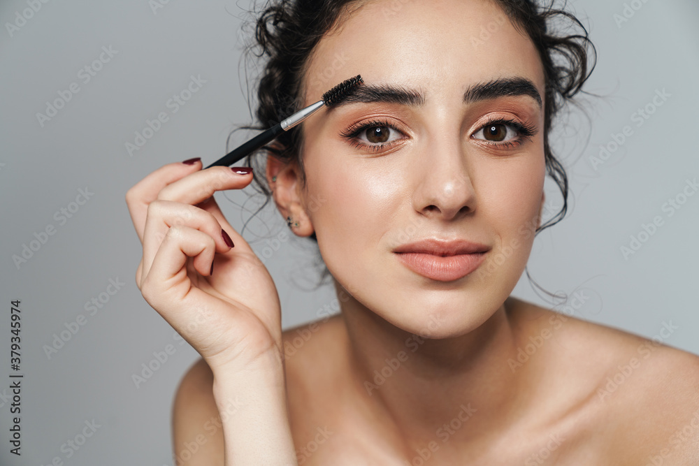 Image of half-naked woman using cosmetic brush for her eyebrows