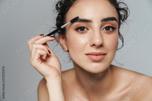 Image of half-naked woman using cosmetic brush for her eyebrows photo