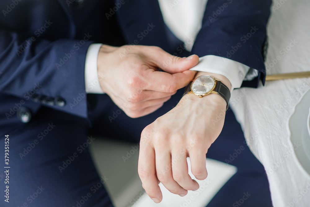 Close-up of a man in a tux fixing his cufflink. groom bow tie cufflinks. Groom adjusts cufflinks, groom in a blue suit straightens his sleeves.
