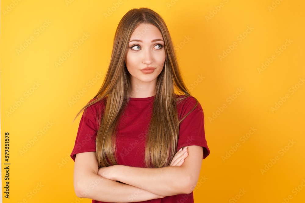 Photo of cheerful positive Beautiful Young beautiful caucasian girl wearing red t-shirt over isolated yellow background, looking aside into empty space thoughtful isolated over yellow background Photo of cheerful positive Beautiful Young beautiful caucasian girl wearing red t-shirt over isolated yellow background, looking aside into empty space thoughtful isolated over yellow background