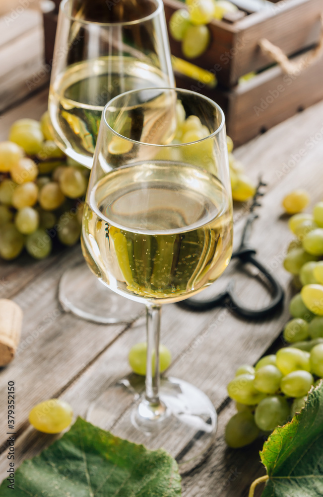 Two glasses of white wine and grape on vintage wooden table