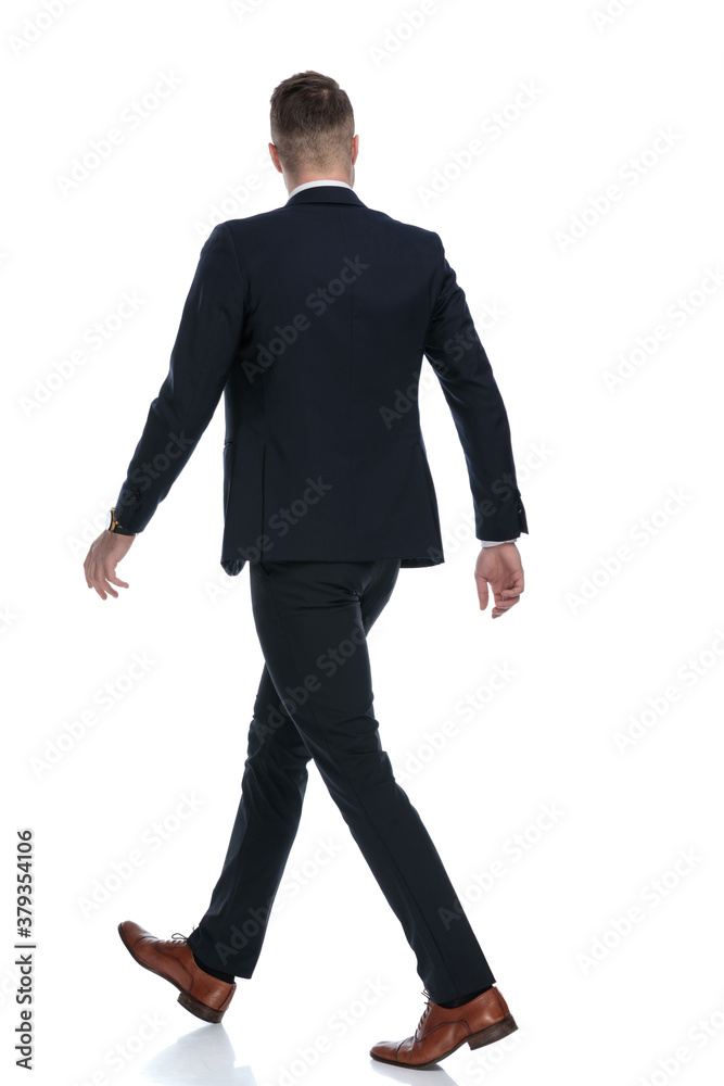 Side rear view of confident wearing suit and walking Side rear view of confident wearing suit and walking