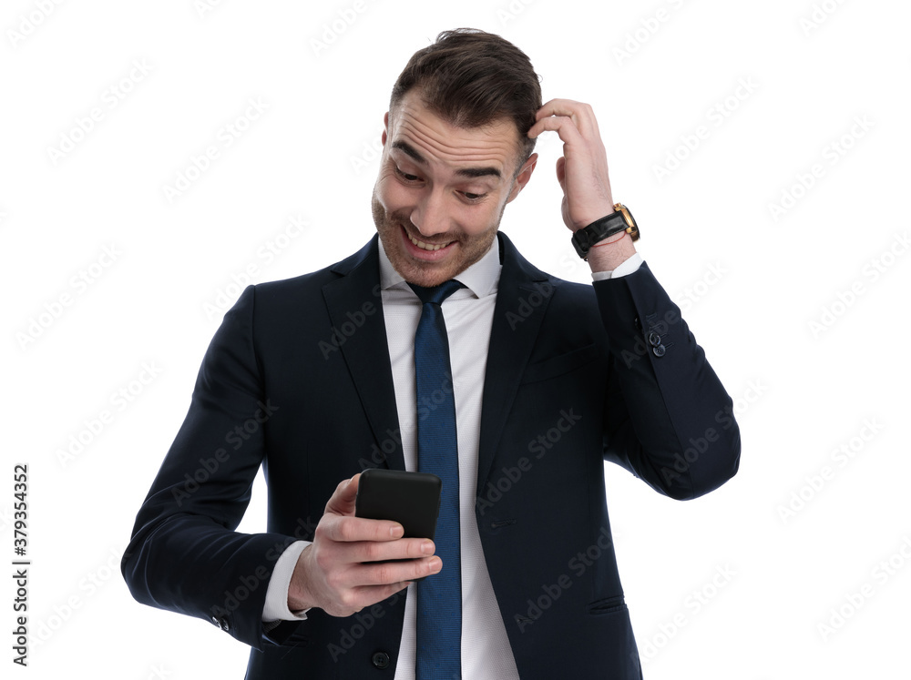 Cheerful businessman looking at phone and laughing, scratching head Cheerful businessman looking at phone and laughing, scratching head