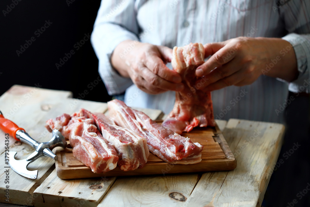 The chef prepares pork ribs on a wooden board. Cooking BBQ ribs. Selective focus.