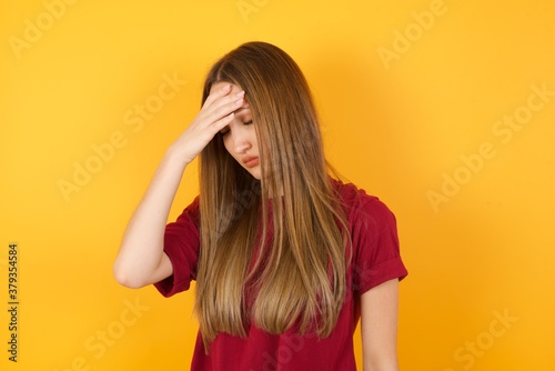 A very upset and lonely Beautiful Young beautiful caucasian girl wearing red t-shirt over isolated yellow background. crying,