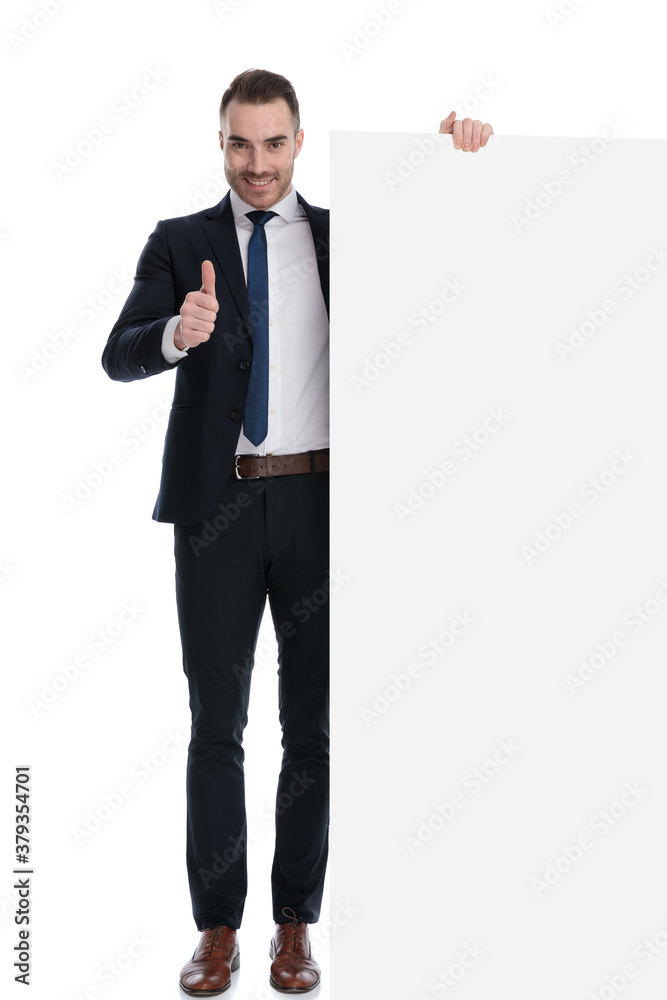 Positive businessman gesturing ok and holding empty billboard Positive businessman gesturing ok and holding empty billboard