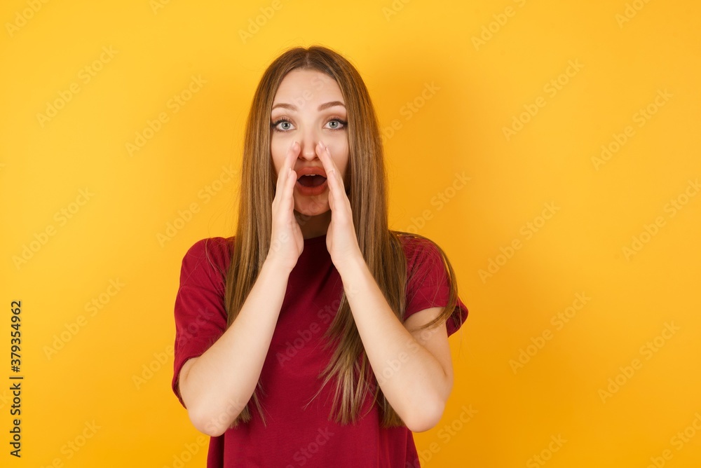 Beautiful Young beautiful caucasian girl wearing red t-shirt over isolated yellow background, shouting excited to front. Beautiful Young beautiful caucasian girl wearing red t-shirt over isolated yellow background, shouting excited to front.