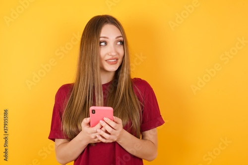 Beautiful Young beautiful caucasian girl wearing red t-shirt over isolated yellow background holding in hands showing new cell