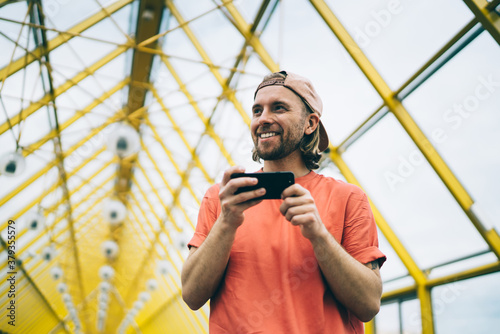 Smiling hipster watching smartphone in city