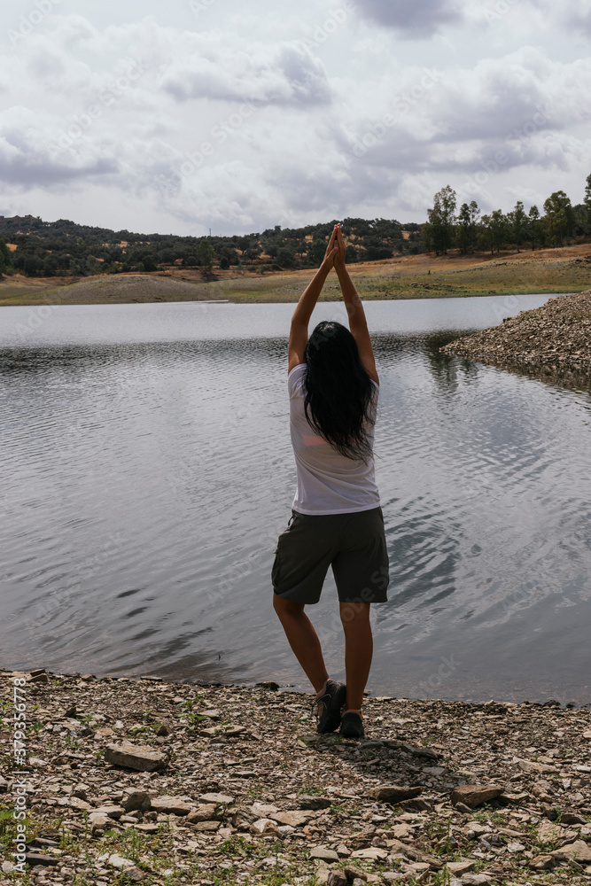Woman doing yoga posture near a lake