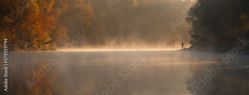 Men fishing in river with fly rod during summer morning. Beautiful fog.