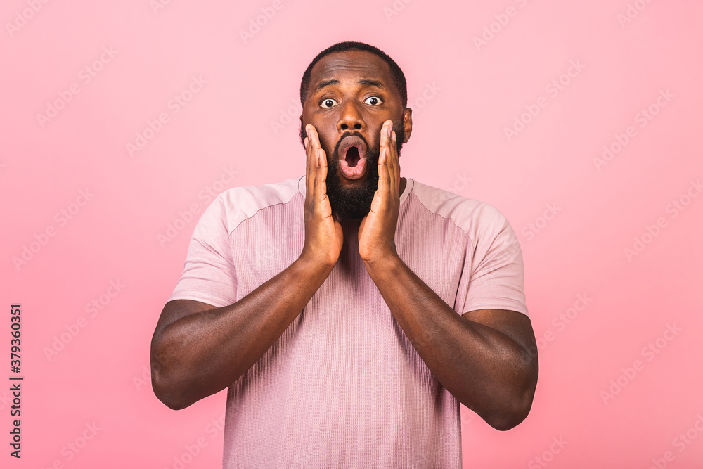 Surprised amazed african american man guy in casual isolated on pink background studio portrait. People lifestyle concept. Mock up copy space. Keeping mouth open.
