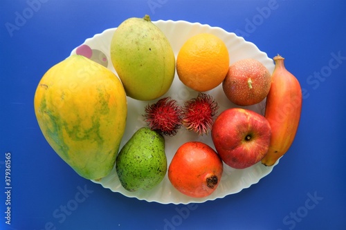 Healthy natural fruits on white plate ,top view,blue background