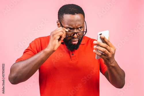 Photography Closeup portrait of handsome young man, shocked, surprised, wide open mouth, mad by what he sees on his cell phone, isolated on pink background