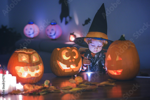 Child, toddler boy, playing with carved pumpkin at home on Halloween