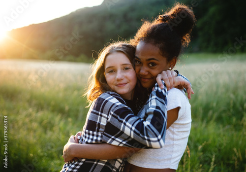 Front view of young teenager girls friends outdoors in nature, hugging. photo