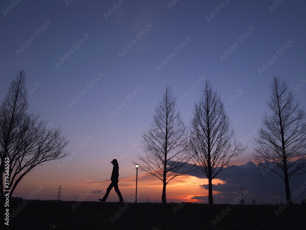 夕焼けを見ながら散歩している人のシルエット