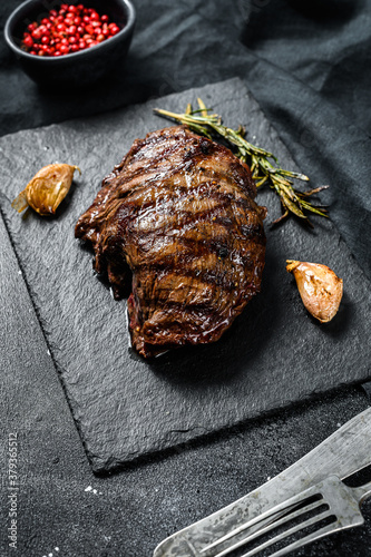Grilled Top Blade steak on a stone Board, marbled beef. Black background. Top view