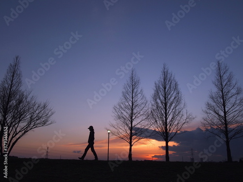 夕焼けを見ながら散歩している人のシルエット