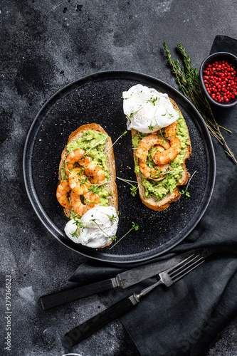 Bread with guacamole, fried shrimp, prawns and egg. Black background. Top view
