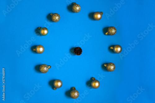 Christmas banner with gold christmas balls and bump clock-shaped on blue background. New year flatlay