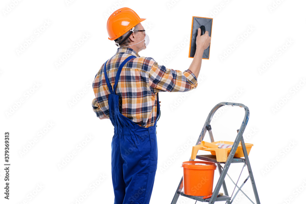 Plasterer man in mask at work with trowel plastering the wall of interior, wear helmet, white wall with copy space background Plasterer man in mask at work with trowel plastering the wall of interior, wear helmet, white wall with copy space background