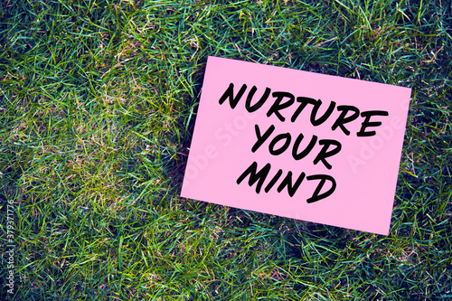 Nurture your mind quote written on paper on green grass background. The effect of thoughts on mind and body concept. © Cagkan