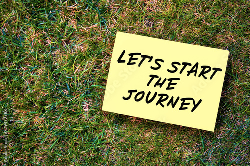 Let's start the journey message written on paper on grass background. Inspirational quote to create future in business or life. © Cagkan