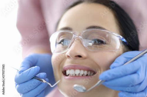 Young woman at dentist s office with instruments in her hands. Dental treatment and prosthetics concept.
