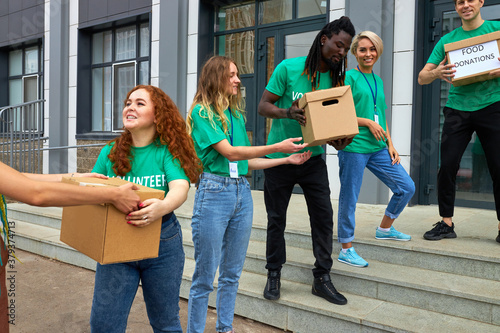 active young people enjoys volunteering at food and clothes bank, voluntary company. diverse people working in voluntary company with friends putting food for donation into boxes